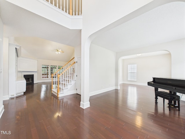 7501 Montibillo Pkwy, Durham, NC 27713 - living area featuring arched walkways, a fireplace, stairs, dark wood-style floors, and a towering ceiling