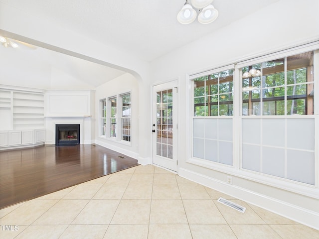 7501 Montibillo Pkwy, Durham, NC 27713 - unfurnished living room with lofted ceiling, a fireplace with flush hearth, and tile patterned flooring