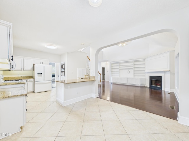 7501 Montibillo Pkwy, Durham, NC 27713 - kitchen with white refrigerator with ice dispenser, arched walkways, open floor plan, light stone countertops, and recessed lighting