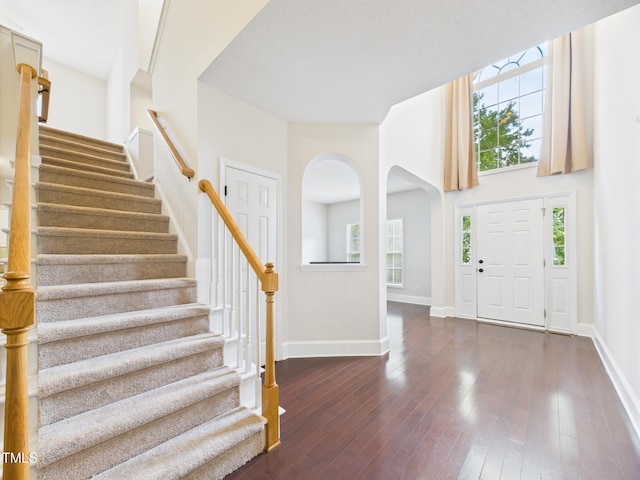 7501 Montibillo Pkwy, Durham, NC 27713 - foyer with stairway, plenty of natural light, arched walkways, dark wood-type flooring, and a high ceiling