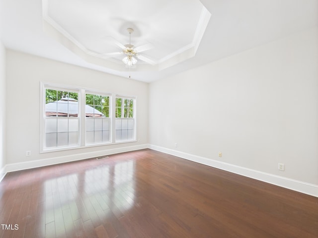 7501 Montibillo Pkwy, Durham, NC 27713 - empty room featuring a raised ceiling, a ceiling fan, crown molding, and dark wood-style floors