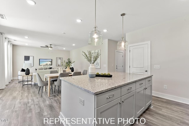7678 New Sandy Hill Church Rd, Sims, NC 27880 - kitchen with a ceiling fan, light wood-type flooring, recessed lighting, a center island, and light stone counters