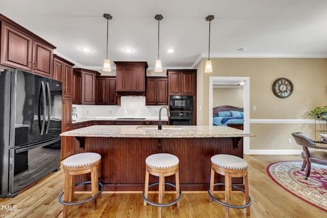 3728 Marwick Ct, Wendell, NC 27591 - kitchen featuring black appliances, light wood-type flooring, decorative backsplash, pendant lighting, and a breakfast bar area