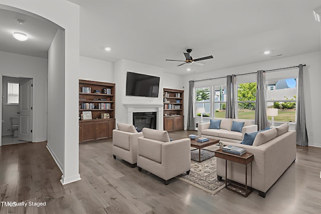 1414 Arena Ln, Fuquay Varina, NC 27526 - living area with ceiling fan, a glass covered fireplace, arched walkways, light wood-style floors, and recessed lighting