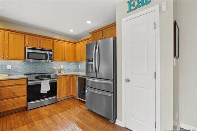 104 Somerset Dr, Raeford, NC 28376 - kitchen featuring appliances with stainless steel finishes, light countertops, wine cooler, light wood-style floors, and brown cabinets