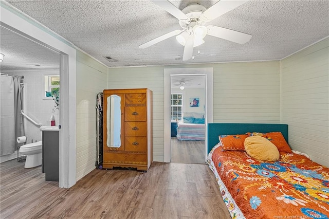 944 Cain Rd, Saint Pauls, NC 28384 - bedroom with a textured ceiling, wood finished floors, ceiling fan, ensuite bath, and wood walls