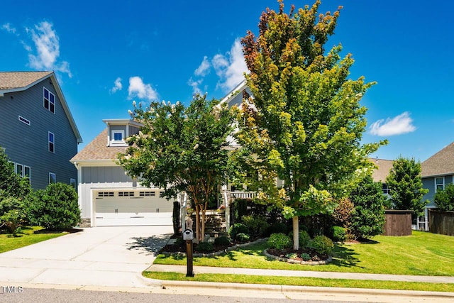 42 Juneberry Dr, Chapel Hill, NC 27516 - view of property hidden behind natural elements featuring board and batten siding, a front yard, concrete driveway, stairs, and a shingled roof