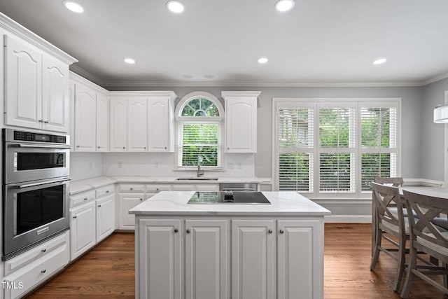 202 Stoneleigh Dr, Cary, NC 27511 - kitchen with black electric cooktop, double oven, ornamental molding, white cabinets, and a center island