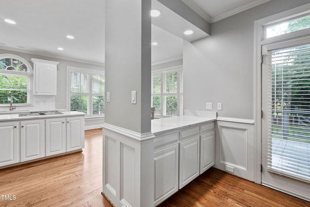 202 Stoneleigh Dr, Cary, NC 27511 - kitchen with ornamental molding, white cabinetry, light wood-style floors, a peninsula, and a wainscoted wall