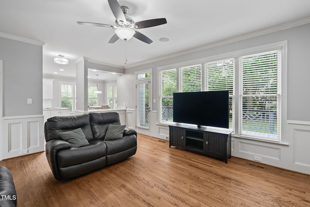 202 Stoneleigh Dr, Cary, NC 27511 - living room with a ceiling fan, a decorative wall, light wood-style floors, crown molding, and a wainscoted wall