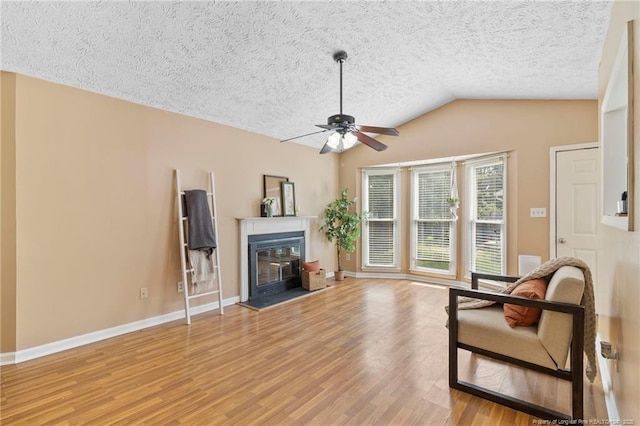 3820 Crusader Dr, Hope Mills, NC 28348 - living area with ceiling fan, wood finished floors, a glass covered fireplace, a textured ceiling, and vaulted ceiling