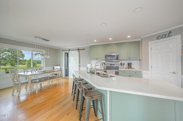 656 Atkins Rd, Fuquay Varina, NC 27526 - kitchen featuring a barn door, appliances with stainless steel finishes, ornamental molding, decorative backsplash, and recessed lighting