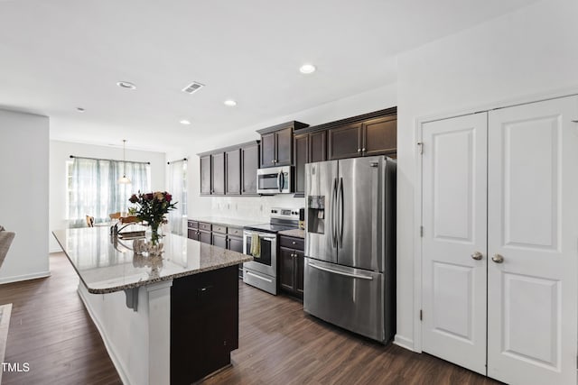 202 E Painted Way, Clayton, NC 27527 - kitchen featuring appliances with stainless steel finishes, light stone countertops, a center island with sink, dark wood-type flooring, and recessed lighting