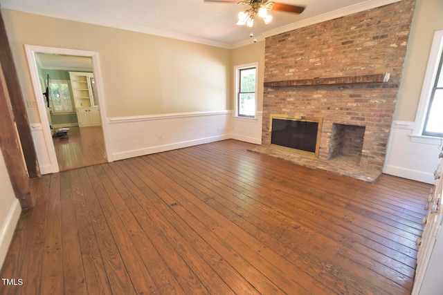 2708 Coleberry Trl, Rocky Mount, NC 27804 - unfurnished living room featuring a ceiling fan, wood-type flooring, wainscoting, a brick fireplace, and plenty of natural light