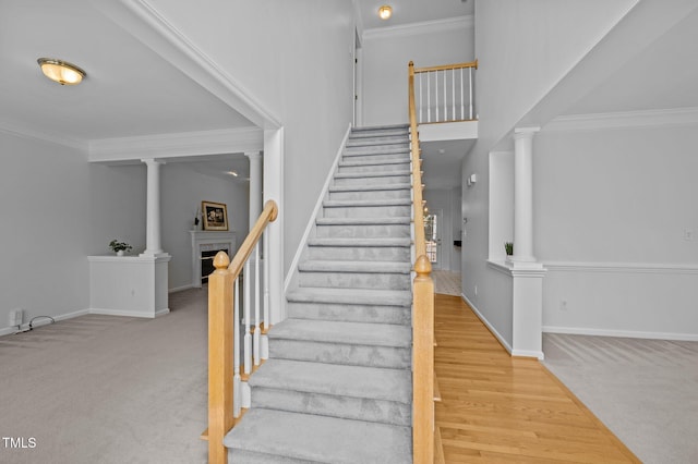 8 Summertime Ct, Durham, NC 27707 - stairway featuring decorative columns, a fireplace, carpet floors, crown molding, and a towering ceiling