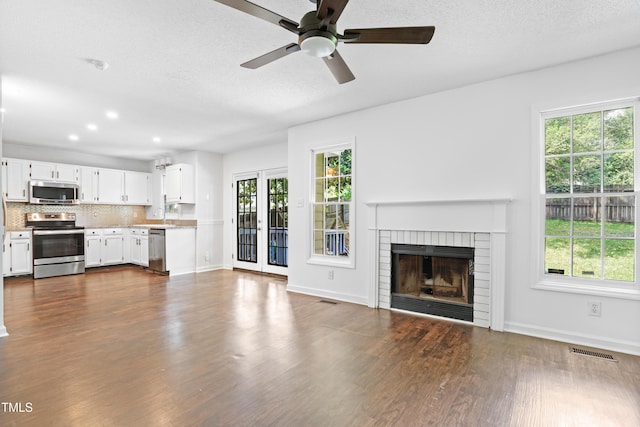 613 Penncross Dr, Raleigh, NC 27610 - unfurnished living room with dark wood finished floors, a fireplace, ceiling fan, a textured ceiling, and recessed lighting