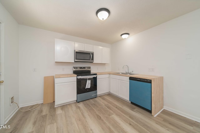 4258 Kaplan Dr, Raleigh, NC 27606 - kitchen featuring stainless steel appliances, light wood-type flooring, white cabinets, and wood counters