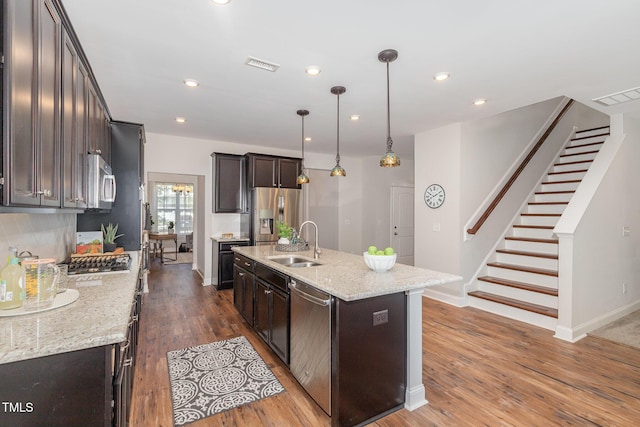 1127 Timbercut Dr, Durham, NC 27703 - kitchen featuring appliances with stainless steel finishes, dark brown cabinets, wood finished floors, a kitchen island with sink, and recessed lighting
