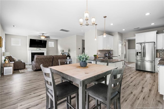 3902 Standardbred Dr, Hope Mills, NC 28348 - dining space with a ceiling fan, light wood-style floors, a fireplace, recessed lighting, and a chandelier