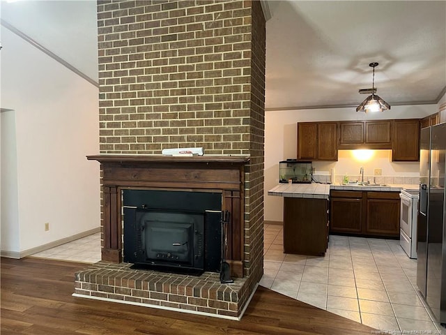 5200 Pineview Rd, Lumberton, NC 28360 - kitchen featuring tile countertops, a fireplace, stainless steel appliances, light wood-style flooring, and crown molding