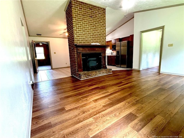 5200 Pineview Rd, Lumberton, NC 28360 - unfurnished living room featuring ornamental molding, ceiling fan, light wood-style flooring, a brick fireplace, and lofted ceiling