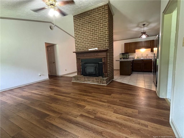 5200 Pineview Rd, Lumberton, NC 28360 - unfurnished living room featuring a ceiling fan, a fireplace, light wood-style floors, lofted ceiling, and crown molding