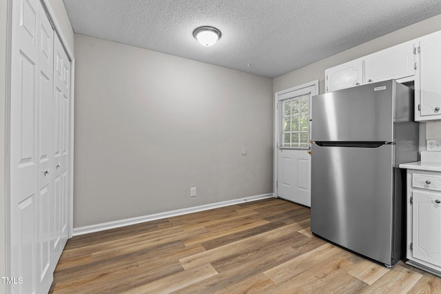113 Fox Run, Henderson, NC 27536 - kitchen with freestanding refrigerator, light wood-style floors, white cabinets, a textured ceiling, and light countertops