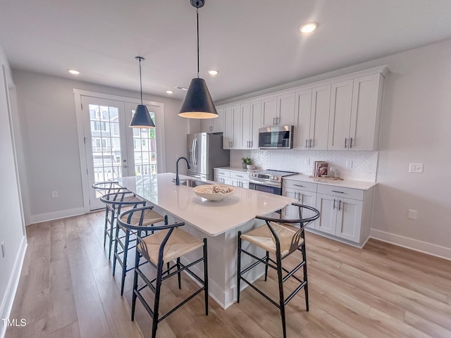 124 Sugar Run Dr Unit 11, Fuquay Varina, NC 27526 - kitchen with stainless steel appliances, a breakfast bar, backsplash, an island with sink, and light wood-style flooring
