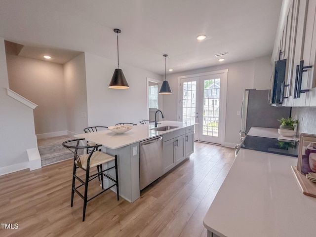 124 Sugar Run Dr Unit 11, Fuquay Varina, NC 27526 - kitchen with stainless steel dishwasher, an island with sink, light wood finished floors, white cabinets, and a breakfast bar area