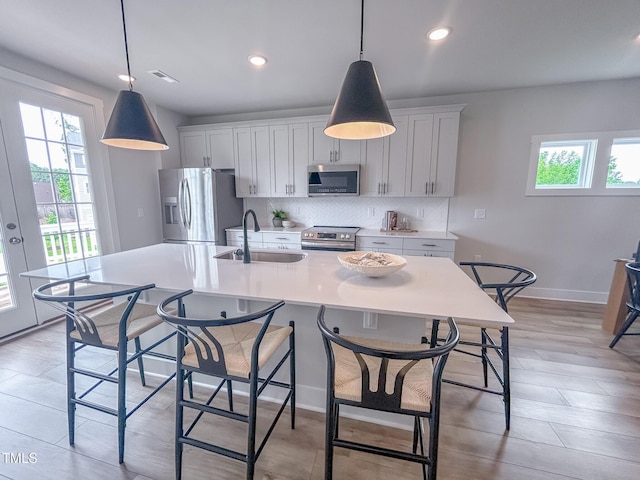 124 Sugar Run Dr Unit 11, Fuquay Varina, NC 27526 - kitchen featuring appliances with stainless steel finishes, light countertops, backsplash, a center island with sink, and a kitchen bar