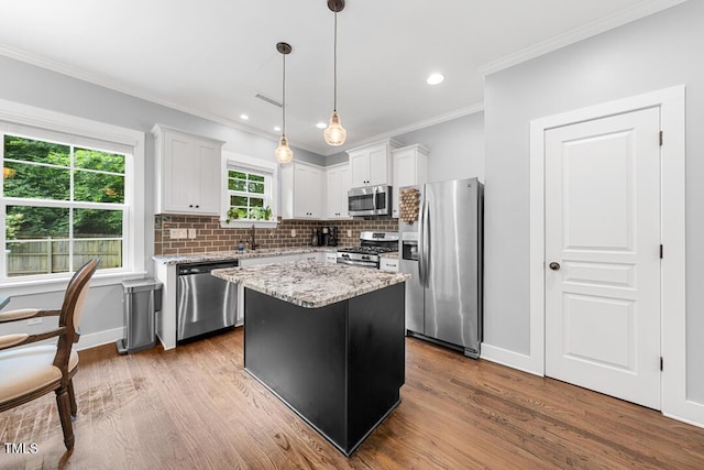 1920 Hart St, Durham, NC 27703 - kitchen featuring stainless steel appliances, crown molding, tasteful backsplash, a kitchen island, and wood finished floors