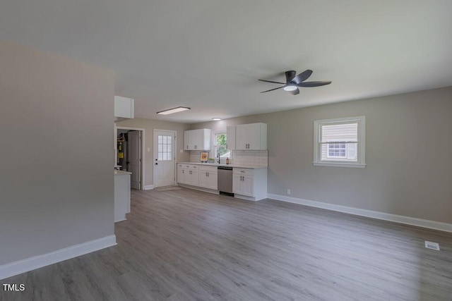 1708 Forest Rd, Durham, NC 27705 - kitchen with stainless steel dishwasher, ceiling fan, wood finished floors, white cabinetry, and healthy amount of natural light