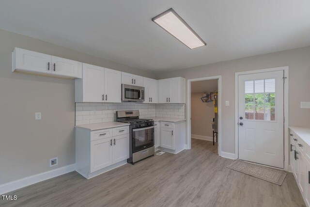 1708 Forest Rd, Durham, NC 27705 - kitchen with stainless steel appliances, light countertops, light wood finished floors, and decorative backsplash
