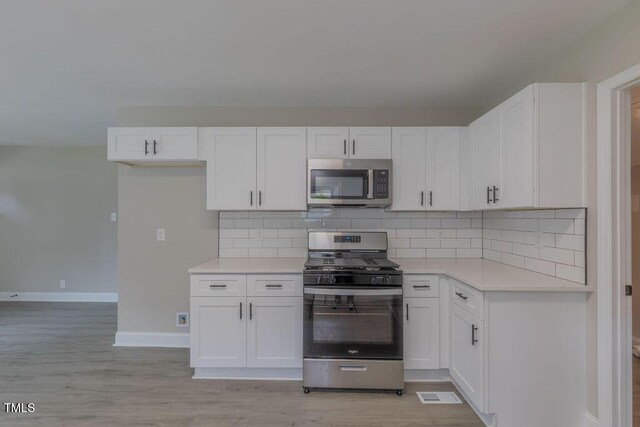 1708 Forest Rd, Durham, NC 27705 - kitchen featuring stainless steel appliances, white cabinets, light countertops, light wood-type flooring, and decorative backsplash