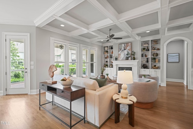 121 Hardy Oaks Way, Holly Springs, NC 27540 - living area featuring a fireplace, light wood-type flooring, a ceiling fan, built in shelves, and beamed ceiling