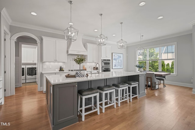 121 Hardy Oaks Way, Holly Springs, NC 27540 - kitchen with premium range hood, independent washer and dryer, light countertops, a spacious island, and crown molding