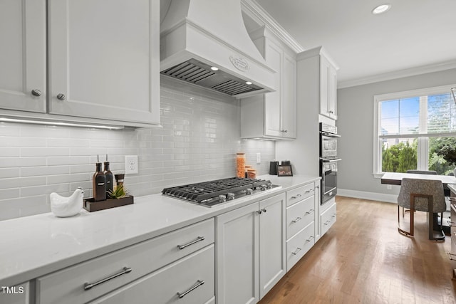 121 Hardy Oaks Way, Holly Springs, NC 27540 - kitchen with wall chimney range hood, appliances with stainless steel finishes, crown molding, light countertops, and tasteful backsplash