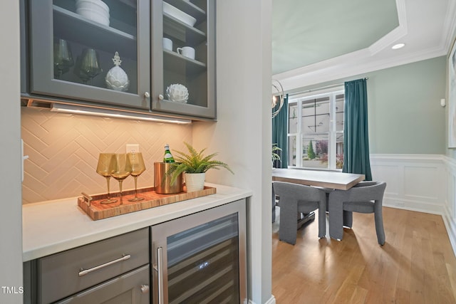 121 Hardy Oaks Way, Holly Springs, NC 27540 - bar featuring beverage cooler, crown molding, decorative backsplash, light wood-style floors, and wainscoting