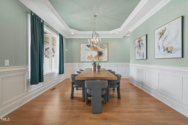 121 Hardy Oaks Way, Holly Springs, NC 27540 - dining room with a chandelier, a raised ceiling, light wood-style floors, crown molding, and wainscoting