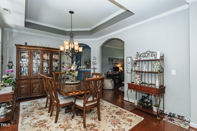 514 Ashley Woods Dr, Gibsonville, NC 27249 - dining space with a chandelier, arched walkways, hardwood / wood-style flooring, a raised ceiling, and ornamental molding