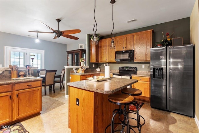 6001 Winged Willet Ct, Wendell, NC 27591 - kitchen with black appliances, brown cabinetry, a kitchen island, and ceiling fan
