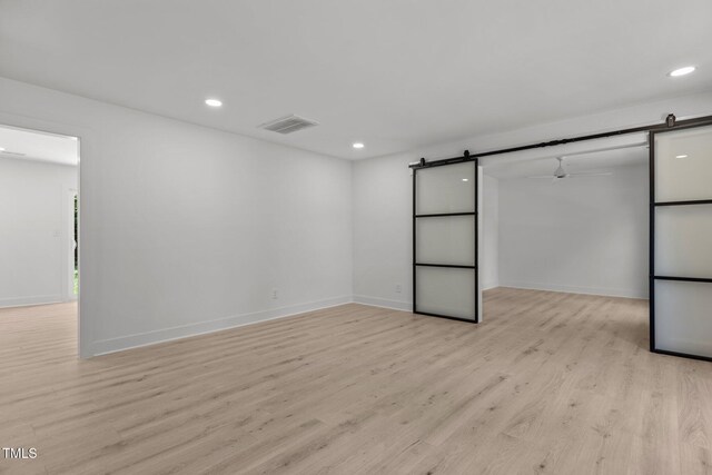 620 Red Carriage Ave, Durham, NC 27704 - unfurnished bedroom featuring a barn door, light wood-type flooring, recessed lighting, and a spacious closet