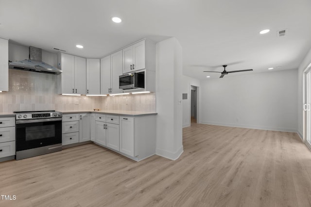 620 Red Carriage Ave, Durham, NC 27704 - kitchen featuring stainless steel appliances, wall chimney range hood, backsplash, ceiling fan, and light wood-type flooring