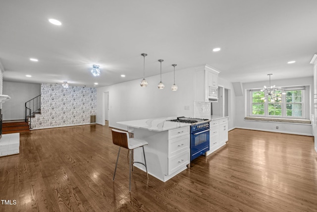 3516 Swift Dr, Raleigh, NC 27606 - kitchen featuring gas range, white cabinetry, light stone countertops, hanging light fixtures, and dark wood finished floors