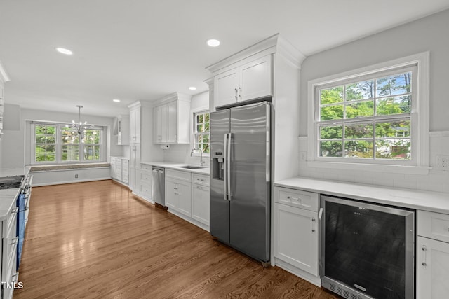 3516 Swift Dr, Raleigh, NC 27606 - kitchen featuring stainless steel appliances, wine cooler, wood finished floors, white cabinetry, and tasteful backsplash