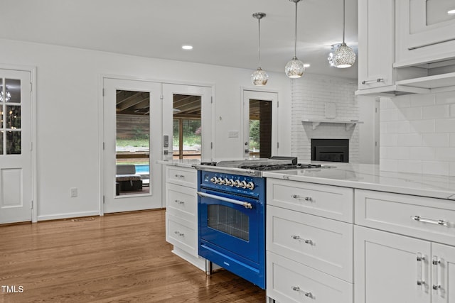 3516 Swift Dr, Raleigh, NC 27606 - kitchen featuring gas range oven, white cabinetry, light wood-style flooring, tasteful backsplash, and a fireplace