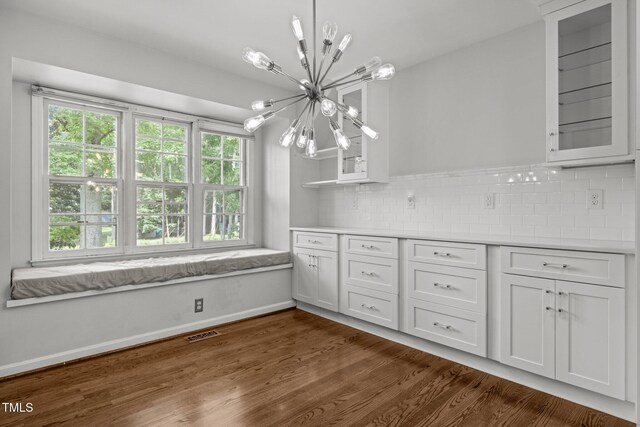 3516 Swift Dr, Raleigh, NC 27606 - kitchen with a chandelier, white cabinetry, tasteful backsplash, dark wood-style floors, and glass insert cabinets