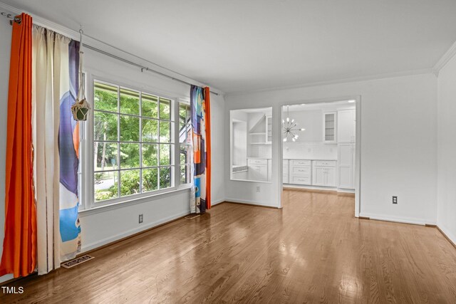 3516 Swift Dr, Raleigh, NC 27606 - unfurnished room with wood finished floors, plenty of natural light, a chandelier, and crown molding