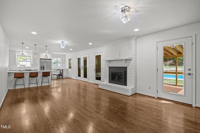 3516 Swift Dr, Raleigh, NC 27606 - unfurnished living room with recessed lighting, wood finished floors, and a brick fireplace
