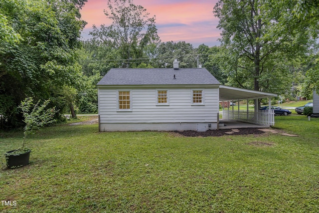 603 S Third St, Mebane, NC 27302 - back of house at dusk with an attached carport, a lawn, a shingled roof, and a chimney